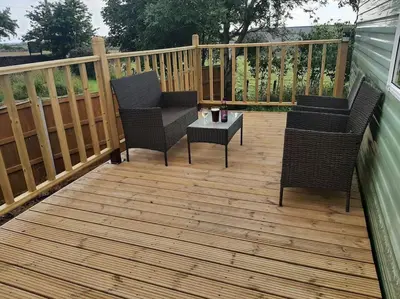 two chairs and a table on a wooden deck at Cadwgan Caravan in Dyffryn