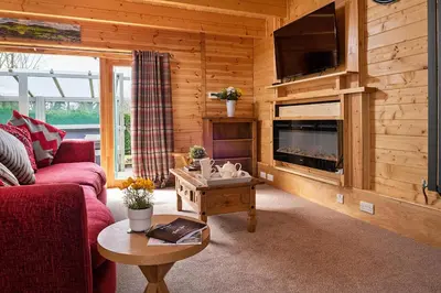 a living room with a couch and a tv and a table at Finest Retreats - Garden Lodge in Craven Arms