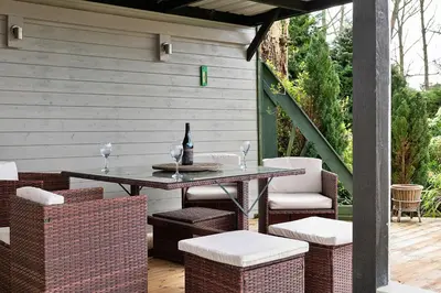 a table and chairs on a patio with a bottle of wine at Finest Retreats - Garden Lodge in Craven Arms