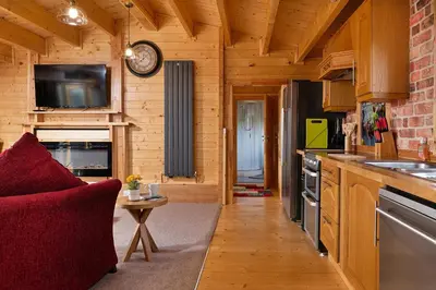 a kitchen with a red couch in a wooden cabin at Finest Retreats - Garden Lodge in Craven Arms