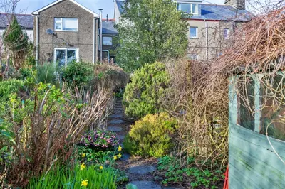 a garden with flowers and plants in front of a house at Finest Retreats - Dolwar Cottage in Ffestiniog