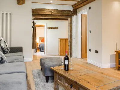 a living room with a bottle of wine on a table at Wheelwright Cottage in Clunbury