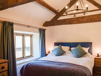 a bedroom with a large bed and a window at Wheelwright Cottage in Clunbury