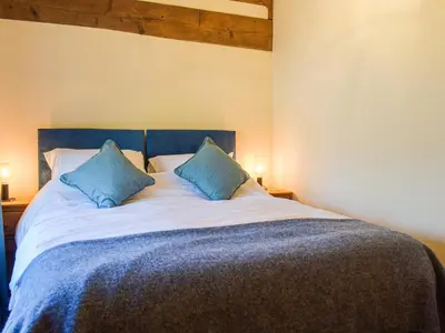 a bedroom with a large bed with blue pillows at Wheelwright Cottage in Clunbury