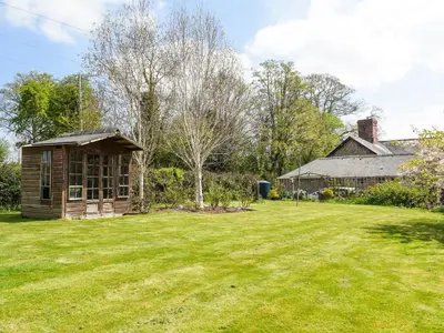 a small house in a yard with a grass field at Wheelwright Cottage in Clunbury