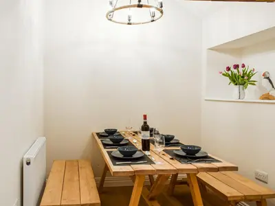 a dining room with a wooden table with wine bottles at Wheelwright Cottage in Clunbury