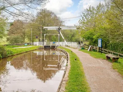 a river with a bridge in the background and a path at Ty Afon in Talybont