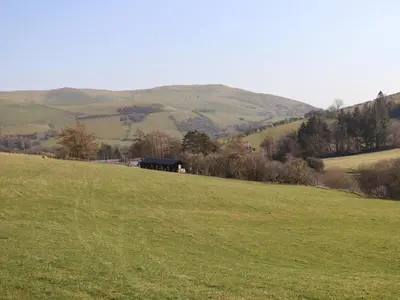 a green field with a barn in the distance at The Sheep Shed in Oswestry