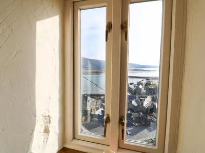 two windows in a room with a view of a city at 2 Bwth Mawr in Barmouth