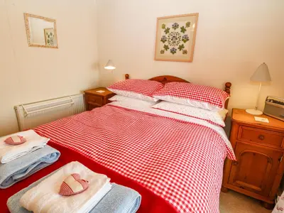 a bedroom with a red and white checked bed at 2 Bwth Mawr in Barmouth