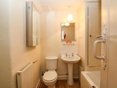 a white bathroom with a toilet and a sink at 2 Bwth Mawr in Barmouth