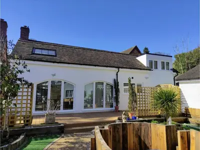 a house with a wooden fence in front of it at A unique and cosy cottage - optional hot tub - Pass the Keys in Church Stretton