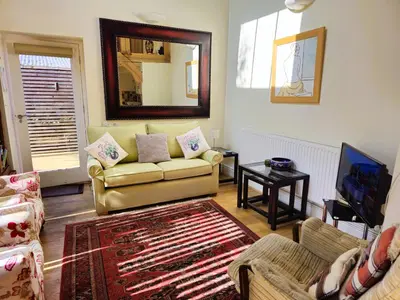 a living room with a couch and a mirror at A unique and cosy cottage - optional hot tub - Pass the Keys in Church Stretton