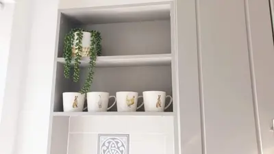 a cupboard with a row of white cups and a plant at Central cosy home 5 minutes walk from Shrewsbury - Pass the Keys in Shrewsbury