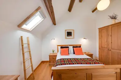 a bedroom with a bed with orange pillows and a ladder at 1 Bed in Dolgellau oc-bow283 in Trawsfynydd