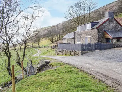 a stone house on the side of a dirt road at Blaen Y Cwm in Carno