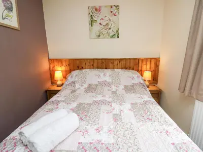a bedroom with a bed with a quilt on it at Primrose Cottage in Llandrindod Wells
