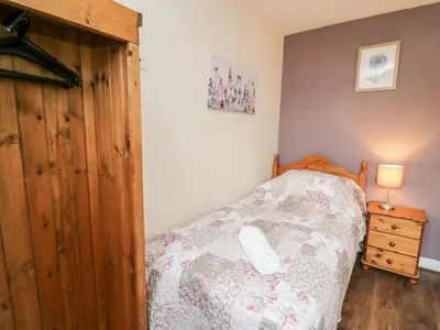 a bedroom with a bed and a wooden closet at Primrose Cottage in Llandrindod Wells