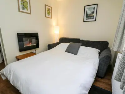 a bedroom with a white bed and a couch at Honeysuckle Cottage in Llandrindod Wells