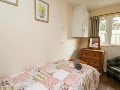 a bedroom with a bed with a quilt on it at Honeysuckle Cottage in Llandrindod Wells