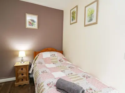 a bedroom with a bed with a quilt on it at Honeysuckle Cottage in Llandrindod Wells