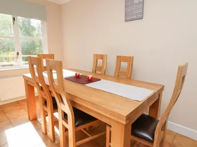 a dining room table with chairs and a board on it at Glyn Cottage in Llanon