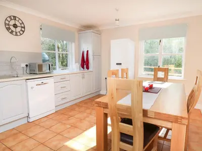 a kitchen with white cabinets and a table and chairs at Glyn Cottage in Llanon