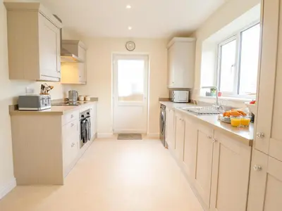 a large kitchen with white cabinets and a window at Mawnog Fach in Bala