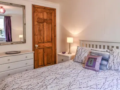 a bedroom with a bed with a mirror and a dresser at Morannedd Bach in Dyffryn