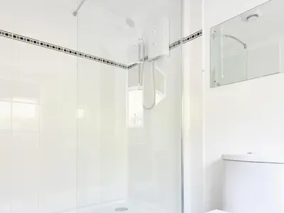a white bathroom with a shower and a sink at Morannedd Bach in Dyffryn