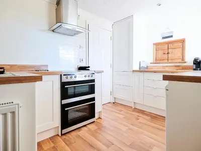 a kitchen with white cabinets and a black oven at Morannedd Bach in Dyffryn