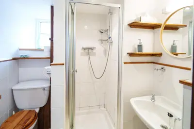 a bathroom with a shower and a toilet and a sink at Brynarth Country Cottages in Aberystwyth