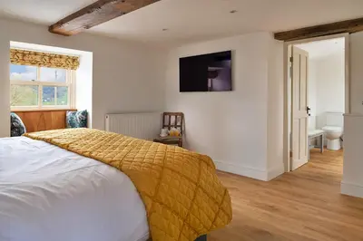 a bedroom with a bed and a television on the wall at Finest Retreats - Moelis Granary - Luxury Cottage with Hot Tub in Llandrillo