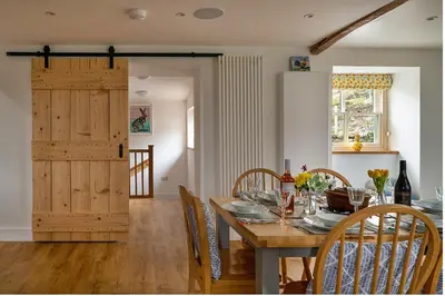 a dining room with a table with chairs and a wooden door at Finest Retreats - Moelis Granary - Luxury Cottage with Hot Tub in Llandrillo