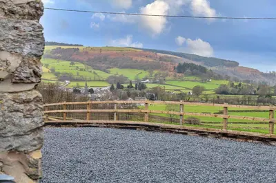 a bridge over a river with a hill in the background at Finest Retreats - Moelis Granary - Luxury Cottage with Hot Tub in Llandrillo
