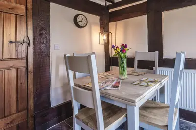 a dining room table with a vase of flowers on it at River Cottage, Melverley in Melverley