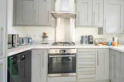 a kitchen with white cabinets and a stove top oven at Modern and bright 2-bed home near Ludlow centre - Pass the Keys in Ludlow