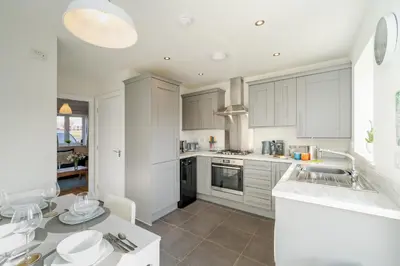 a kitchen with white cabinets and a sink and a table at Modern and bright 2-bed home near Ludlow centre - Pass the Keys in Ludlow