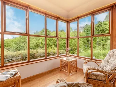 a room with large windows and a table and chairs at Cwmfron House in Llanidloes