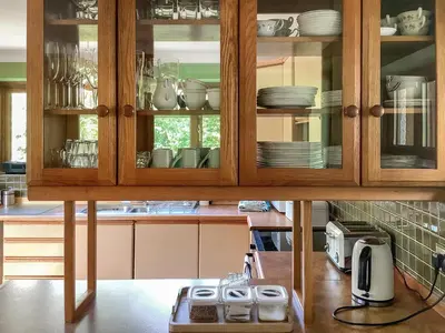 a kitchen with wooden cabinets with plates and dishes at Cwmfron House in Llanidloes