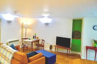 a living room with a couch and a tv and a table at “Dragons Den” Centrally located Modern Apartment in Aberystwyth