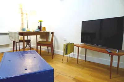 a living room with a flat screen tv and a table at “Dragons Den” Centrally located Modern Apartment in Aberystwyth
