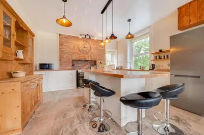 a kitchen with a bar with stools and a fireplace at 5 Bed in Llandovery oc-bow323 in Llangadog