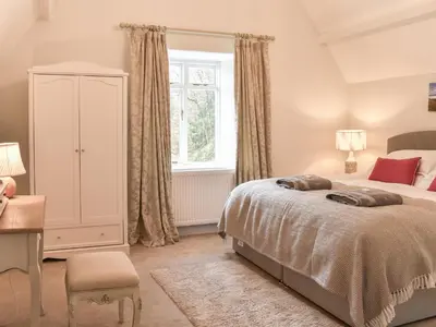 a bedroom with a bed and a dresser and a window at Crogen Gatehouse Lodge in Corwen