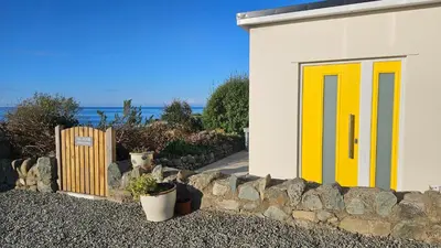 a building with a yellow door and a stone wall at Talarfor Barmouth in Barmouth