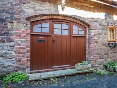 a red door on the side of a brick building at Quaint 1 bedroom cottage in Church Stretton - Pass the Keys in Church Stretton