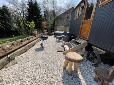 a yard with a house and a stool and a grill at Ty Olwyn Bach, Coity Bach in Brecon