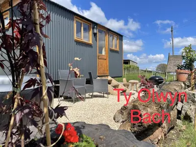 a tiny house in a garden with the words only beach at Ty Olwyn Bach, Coity Bach in Brecon