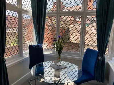 a glass table and two blue chairs in a room with a window at Rooftops - bijou sister apartment to Assembly View - free parking permit provided in Ludlow
