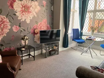 a living room with a television and a blue chair at Rooftops - bijou sister apartment to Assembly View - free parking permit provided in Ludlow